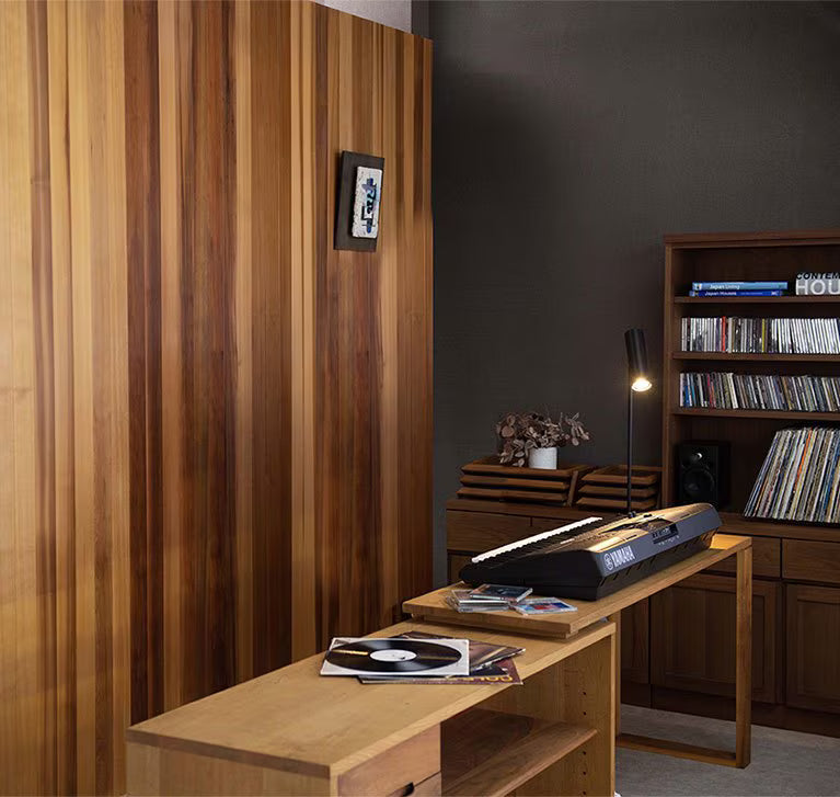 Yamaha PSR-E463 61-key portable keyboard on wooden desk and stand in warm wooden-paneled room interior with bookshelf, vinyl records, plants, desk lamp, and framed art