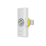 Hollyland Lark M2 shine white Lightning receiver side view plugged into iPhone: white USB-C to Lightning dongle with yellow power button, Hollyland logo, green TX1 and TX2 status LEDs lit, connecting wireless lav mics to iOS devices