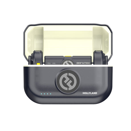 Hollyland Lark M2 (shine charcoal) wireless microphone charging case open: two black TX1 transmitters docked with yellow accents, blue status LED on lid with Hollyland logo, lightweight dual-channel lav system with Lightning receiver