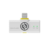 Hollyland Lark M2 shine white Lightning receiver front view: white USB-C to Lightning dongle with yellow power button, Hollyland logo, green TX1 and TX2 pairing LEDs on, "TX1 TX2" labels, plugged into iPhone for dual wireless lavalier audio