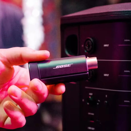 Lifestyle image of Bose S1 Pro+ Wireless Mic/Line Transmitter with an XLR connection, predominantly black in color.